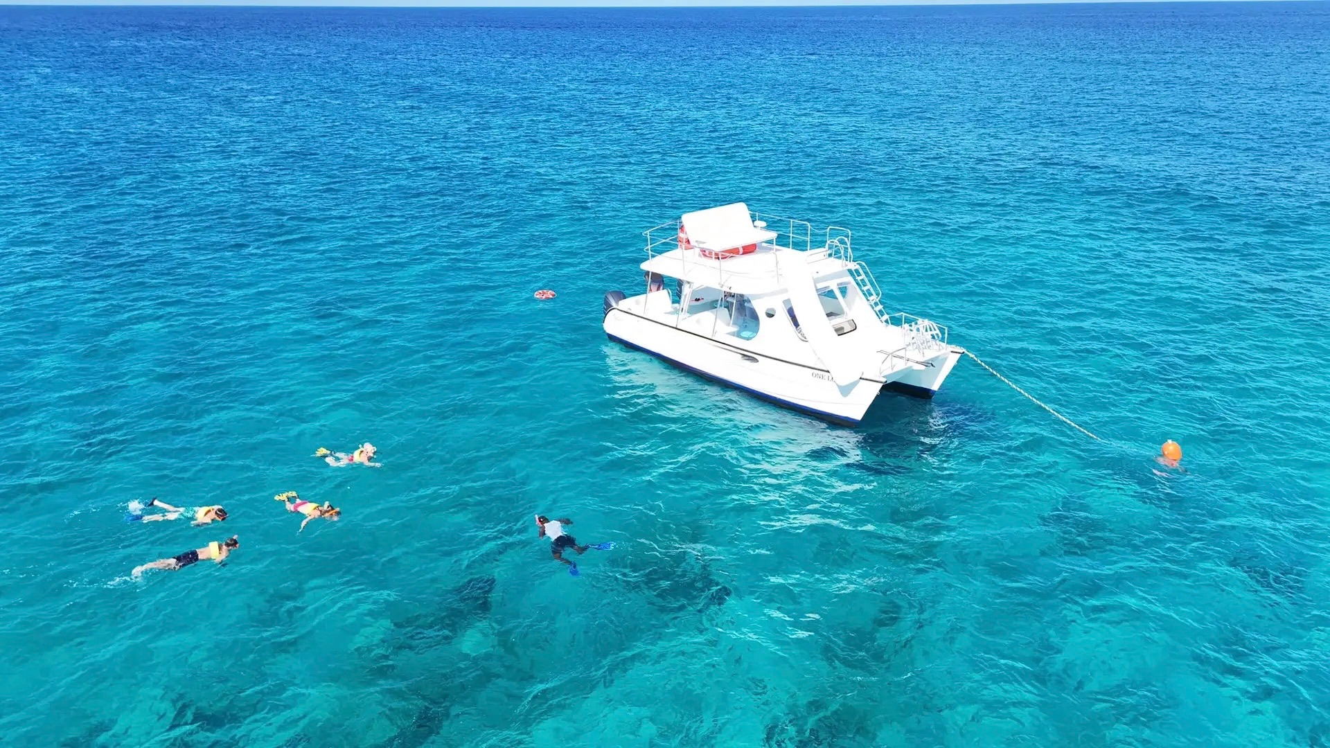 White power catamaran anchored with swimmers snorkelling nearby