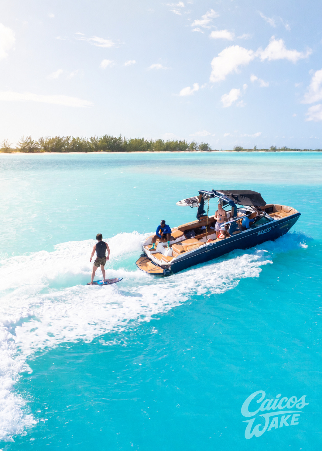 Wake surfer riding behind the Super Air Nautique in turquoise water