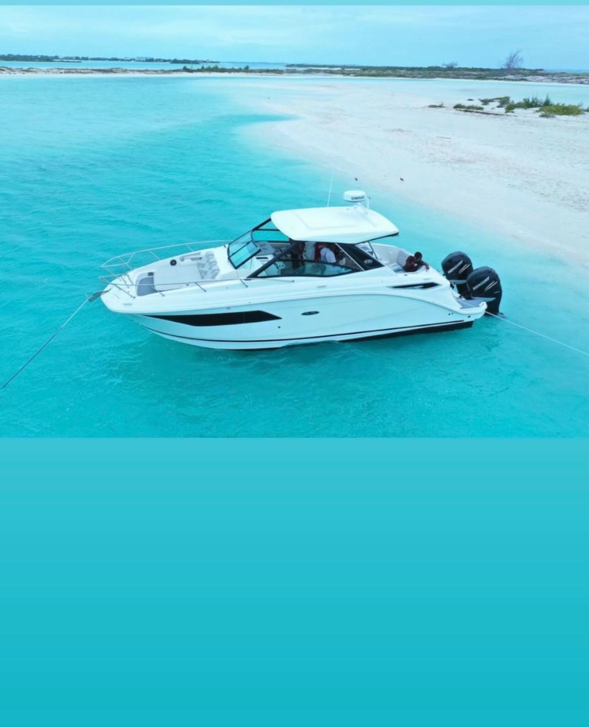 White motor yacht anchored at a turquoise sandbar