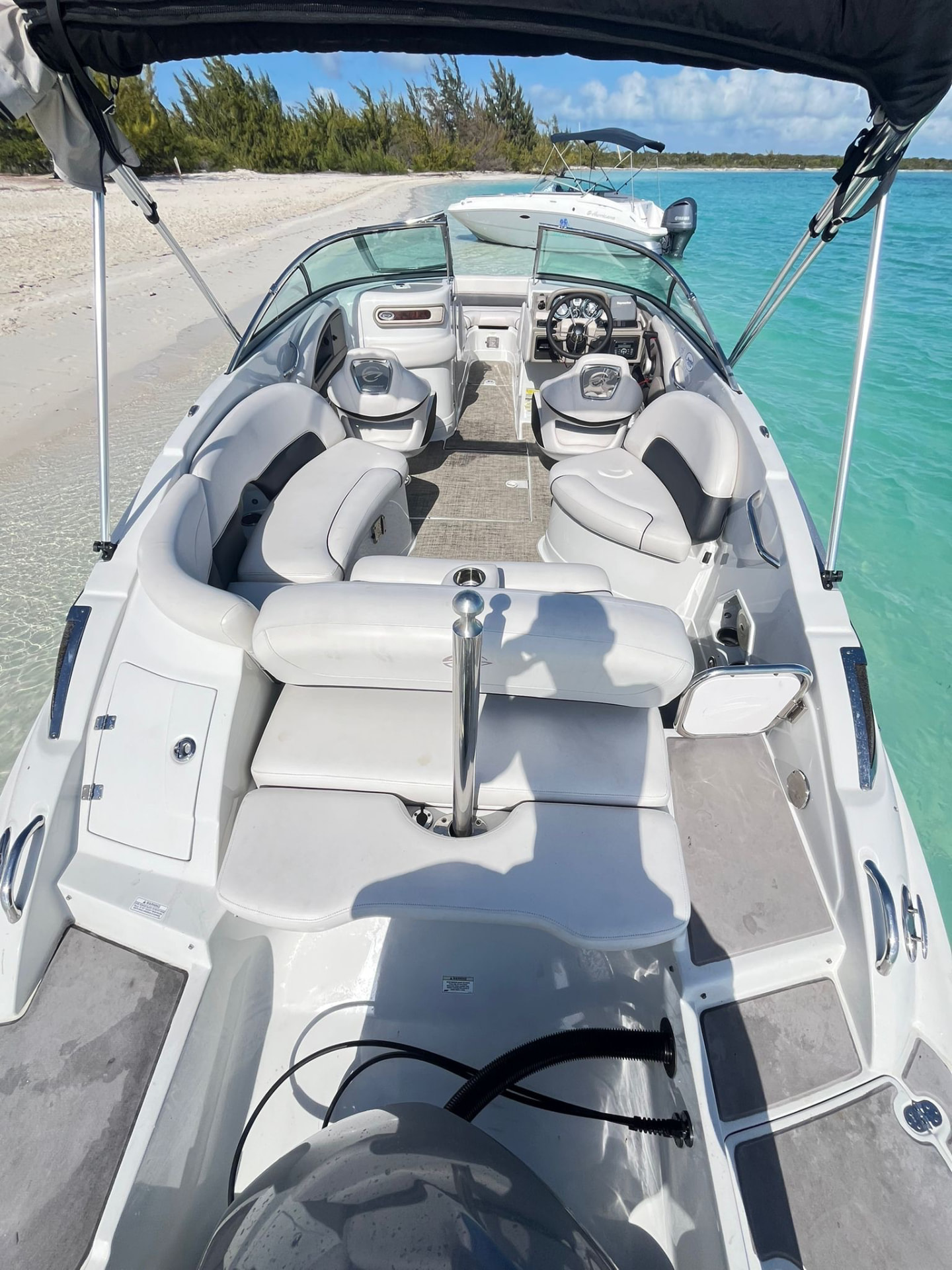Deck boat beached on white sand beside clear turquoise water